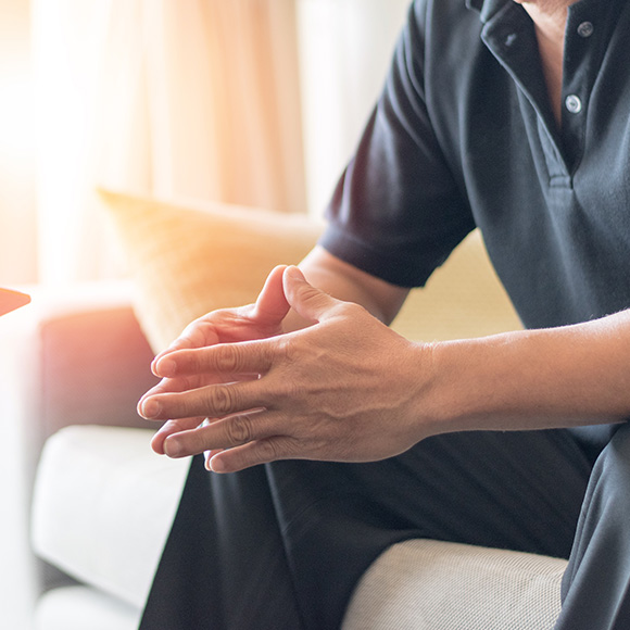 person sitting on a couch with hands clasped in a thoughtful manner in a well-lit room reflecting on three significant ideas