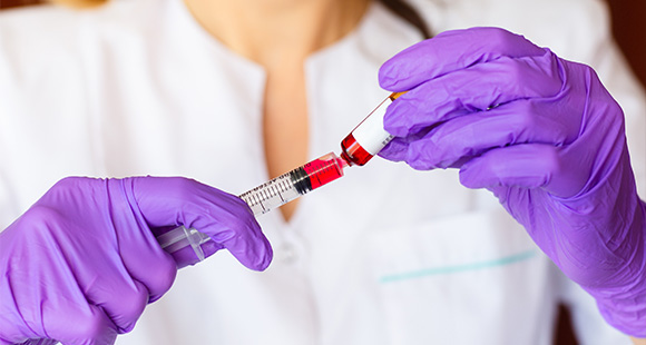 medical professional in purple gloves filling a syringe with red liquid three essential steps for vaccine preparation