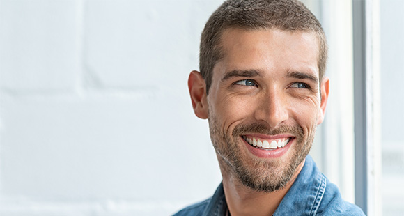 smiling man with short hair wearing a denim jacket against a light background showcasing happiness and positivity expressing confidence with sharp features and a bright smile eight attributes of happiness